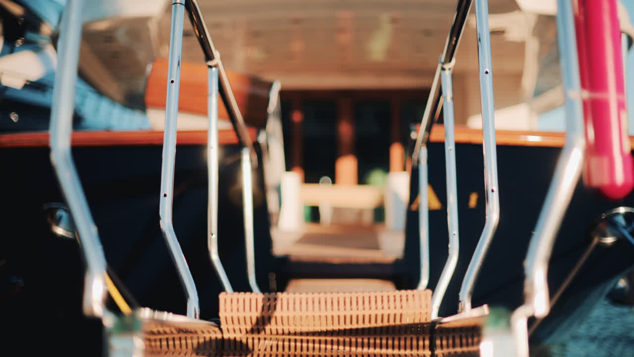 Low angle close up of a yacht gangway leading onboard, with polished chrome handrails and soft golden light
