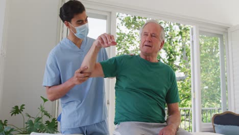 slow motion of male physiotherapist examining senior man's shoulder at nursing home