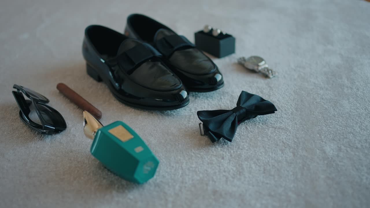 flat lay of groom's wedding day essentials including shoes bow tie cologne and accessories