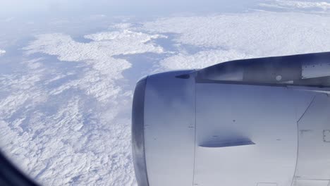 view of an airplane turbine running in the middle of the sky above the clouds