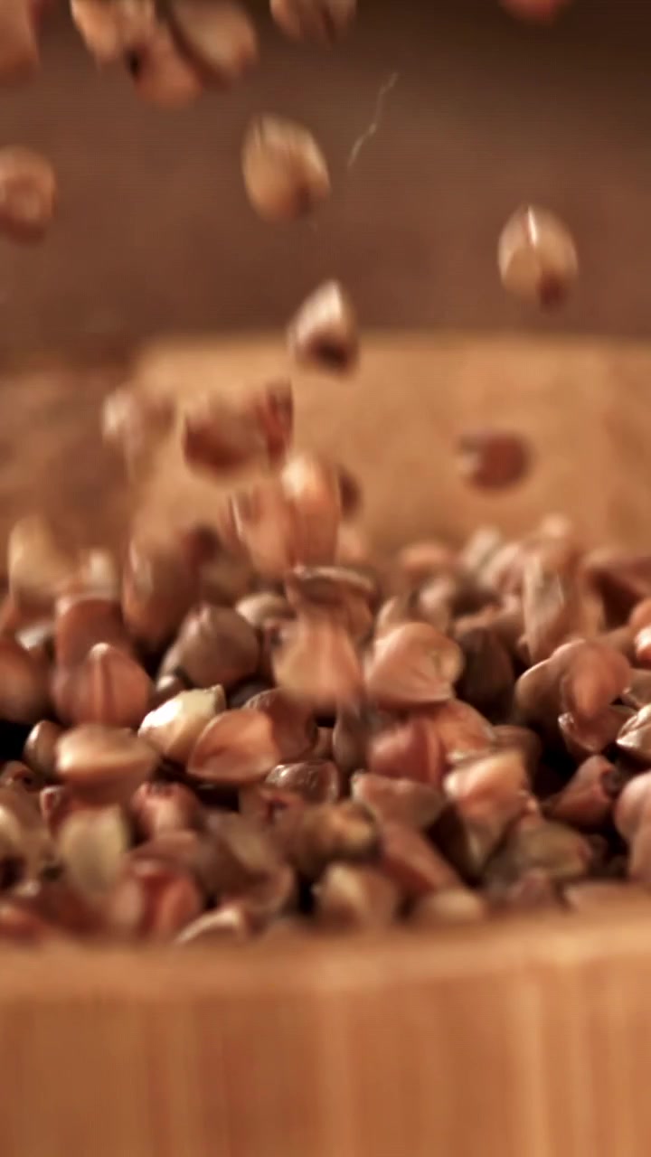 Grano saraceno che cade in una ciotola di legno al rallentatore