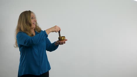 a red-haired woman playing a singing bronze meditation bowl points at a product suggestively