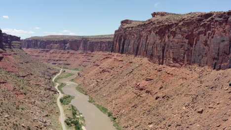 Luftaufnahmen-Des-San-Rafael-Reef-In-Utah,-Die-Die-Atemberaubenden-Roten-Sandsteinklippen-Und-Einen-Gewundenen-Fluss-Zeigen,-Der-Sich-Durch-Die-Wüstenlandschaft-Schlängelt