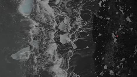 aerial shot directly above waves crashing on an iceberg beach