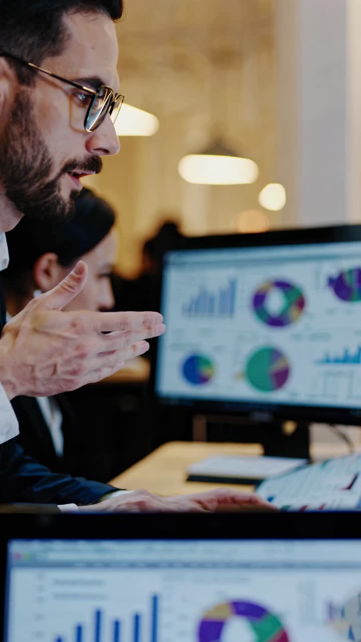 Close-up video shot of professionals analyzing charts on computer screens, highlighting teamwork