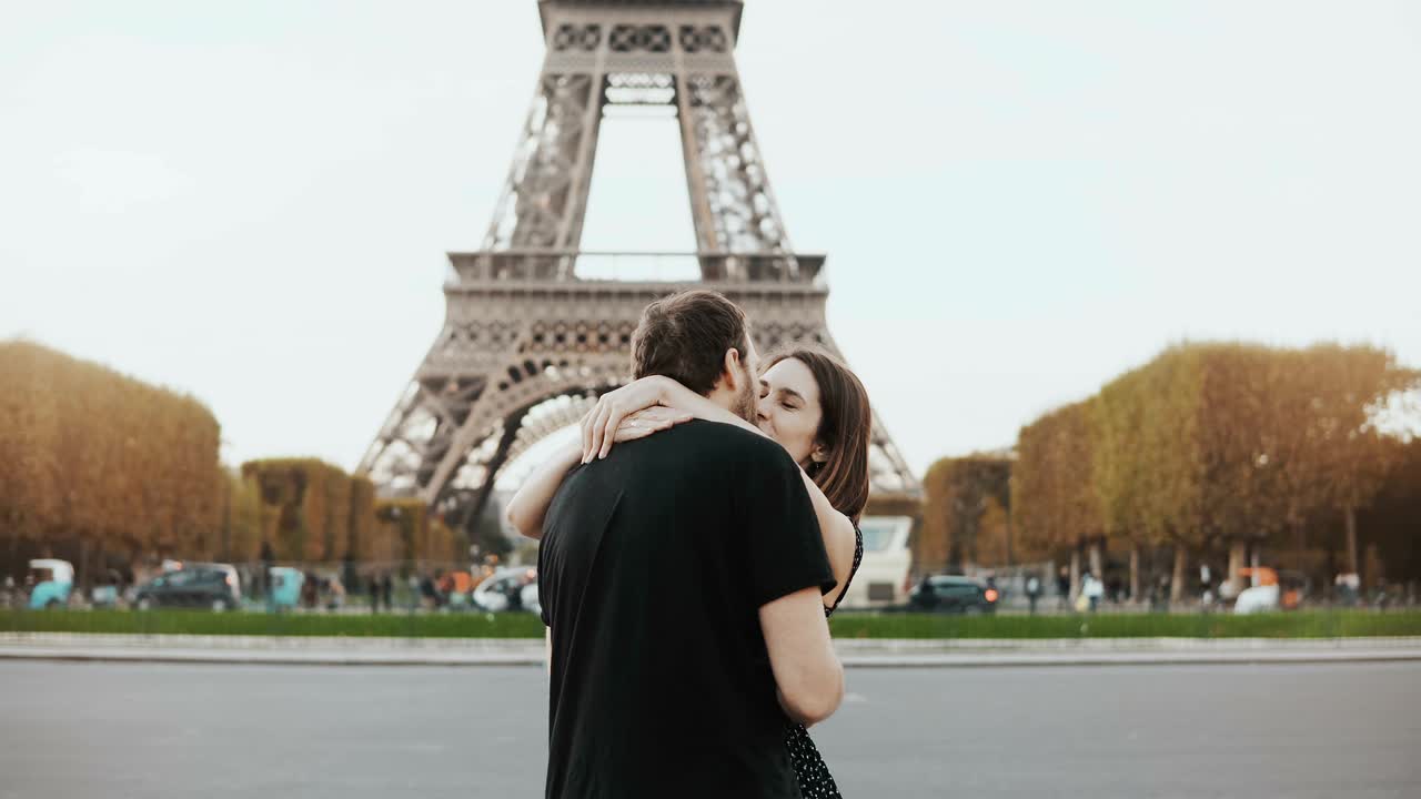 Giovane coppia felice che cammina vicino alla Torre Eiffel a Parigi, Francia. Uomo e donna che si abbracciano e si baciano per strada