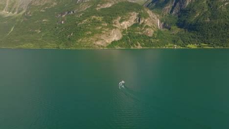 el seguimiento de drones sigue a las embarcaciones acelerando y girando en las aguas verdes del fiordo de lustra, noruega.