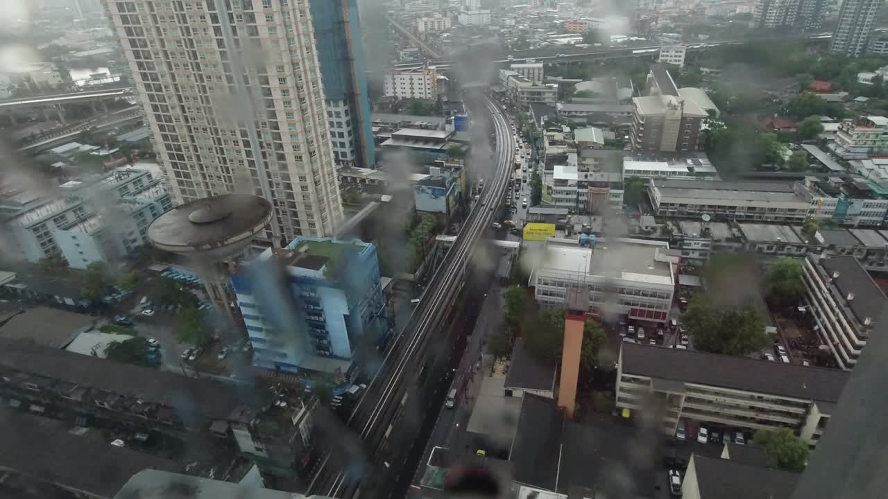 la lluvia cae por la ventana. vista aérea. la lluvia fuera de la ventana de la sala de estar en la temporada de lluvias en bangkok, tailandia. la ventana exterior está borrosa por la lluvia del edificio de la ciudad y la carretera y el cielo.
