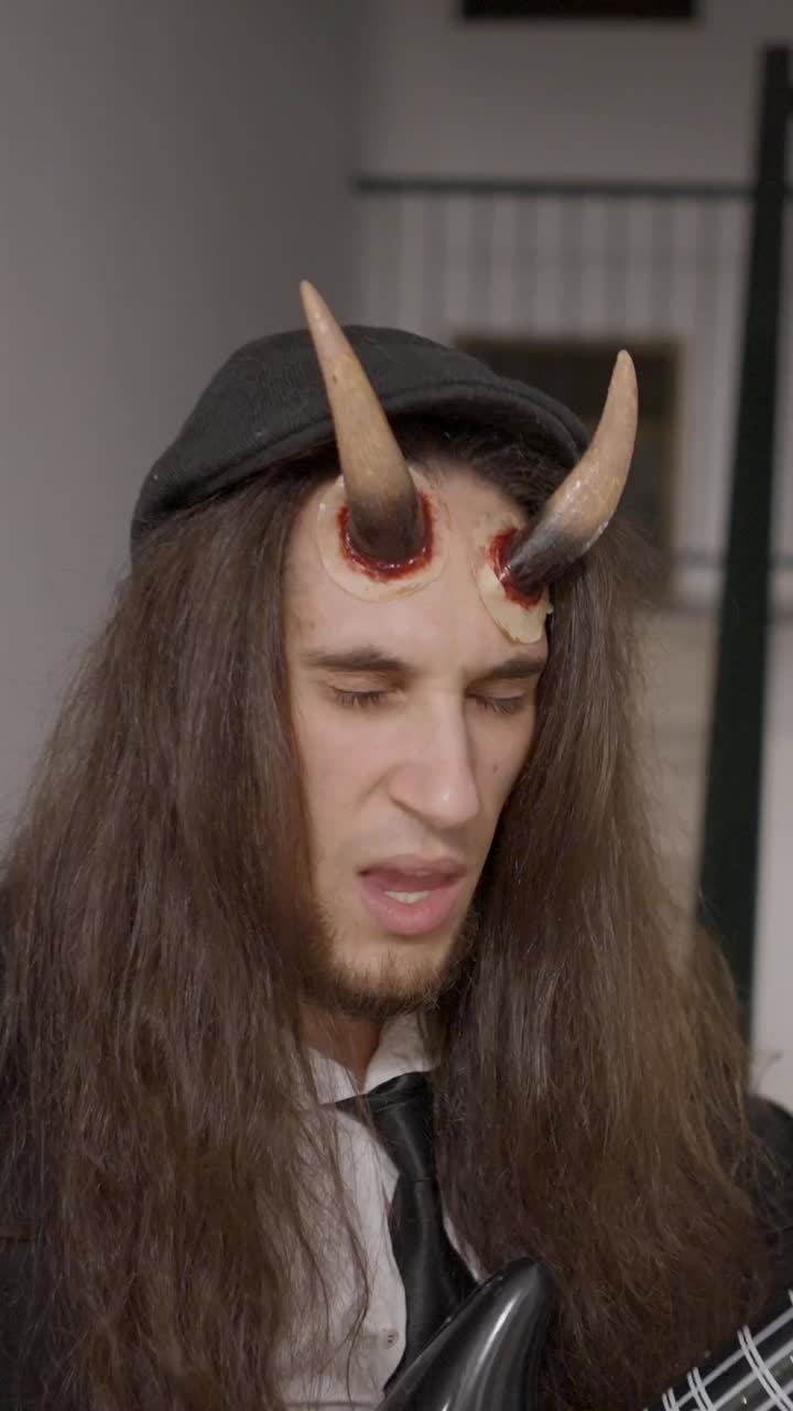 Man in Devil Costume Enthusiastically Playing an Inflatable Guitar