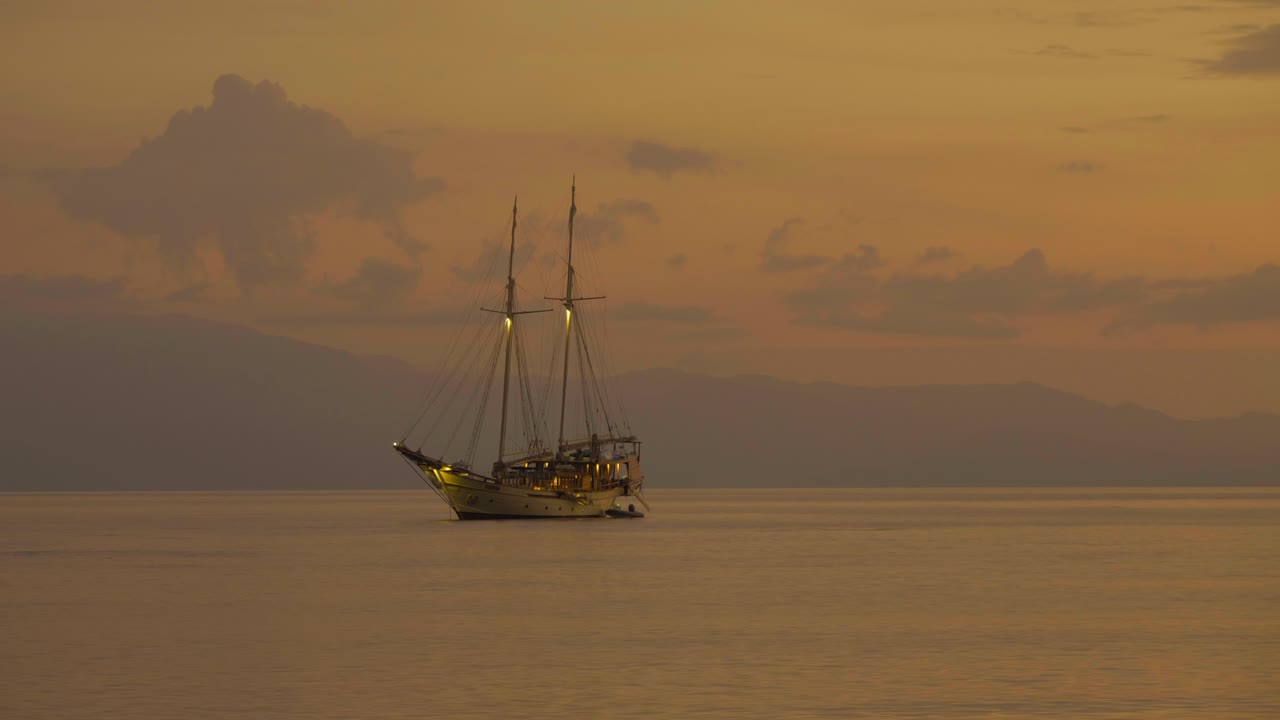 황금 시간 동안 해가 지는 동안 바다 위에 정박 한 항해 보트