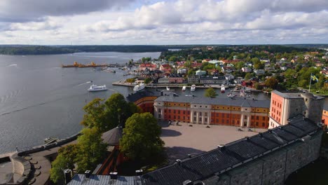 drone shot ascending behind the vaxholm fortress to reveal the town of vaxholm in sweden