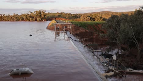 dam wall with water flooding powerfully over it in the remote and normal dry desert outback of australia