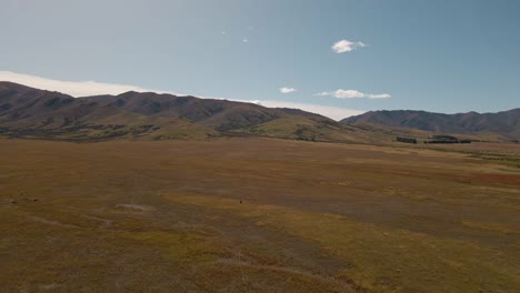 Aerial-approach-towards-wavy-mountain-range-in-vast,-dry-prairie-landscape