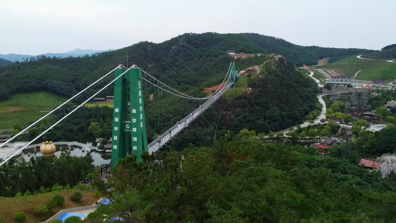 vista aérea del puente de vidrio colgante en el parque temático huaxiacheng en weihai, china