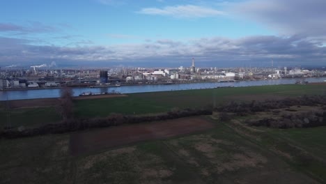agriculture and industry, large industrial estate and green fields separated by river, drone