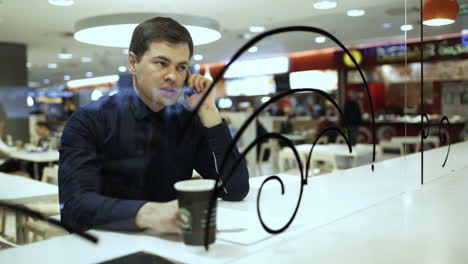 un hombre de negocios hablando por teléfono en un café.