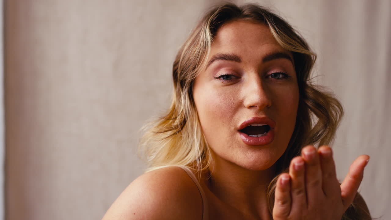fotografía de estudio de una mujer natural y segura en ropa interior promoviendo la positividad corporal soplando un beso