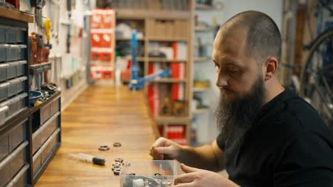 Young-caucasian-repairmen-sitting-at-the-table-with-some-bike-parts