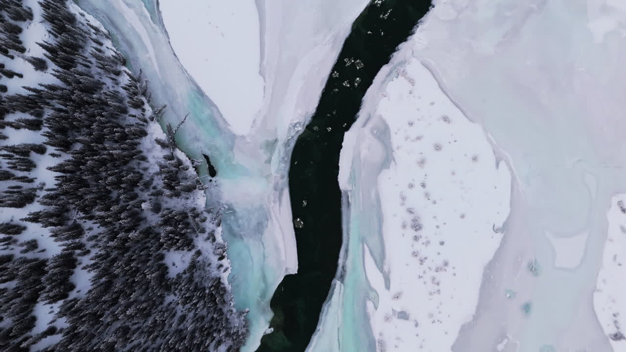 The Takhini River Winding Through a Snowy Landscape, Bordered by Dense Forest in Yukon, Canada - Vertical Shot
