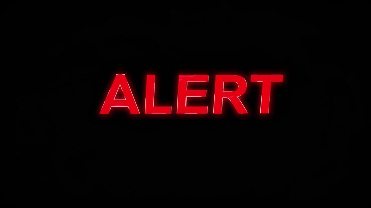 A close-up, eye-level shot of a glowing red 'ALERT' sign against a black background