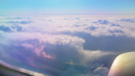 airplane wing view above fluffy clouds stretching out to the horizon, with sunlight reflecting off the aircraft surface