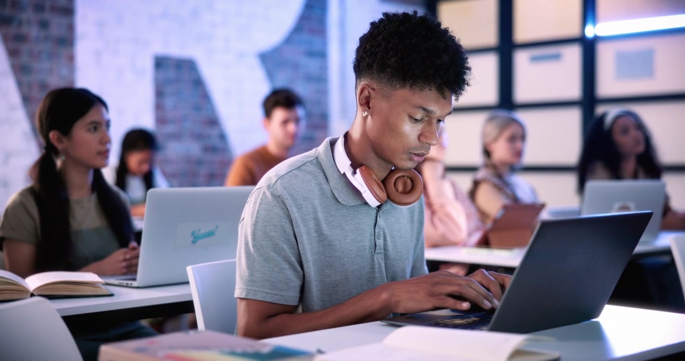 Young Student Typing on Laptop in Classroom