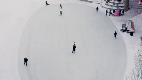 Toma-Aérea-De-Gente-Jugando-Hockey-Sobre-Hielo-Público-En-Las-Bifurcaciones-En-Winnipeg-Manitoba