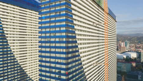 drone footage around facade of modern residential skyscraper under construction