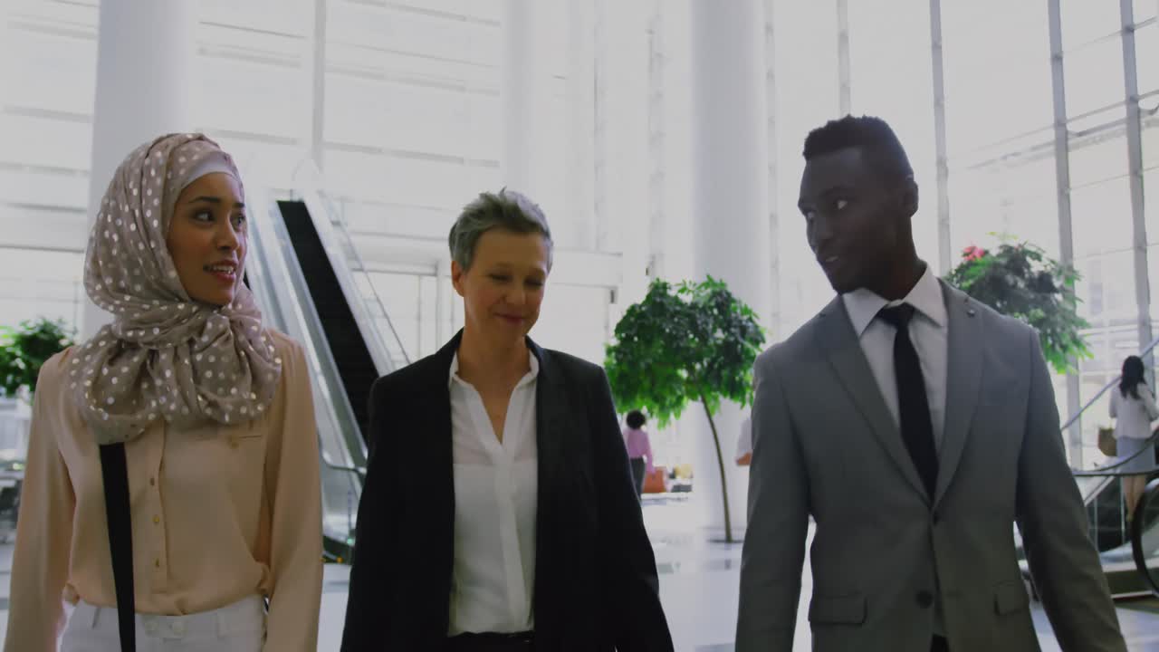 Business people interacting with each other in the lobby at office 4k