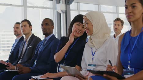 women in the audience at a business seminar talking