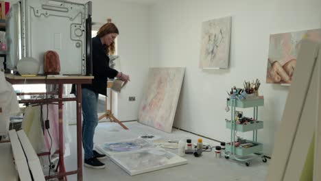 Female-artist-prepping-paper-asset,-on-canvas,-in-a-home-studio