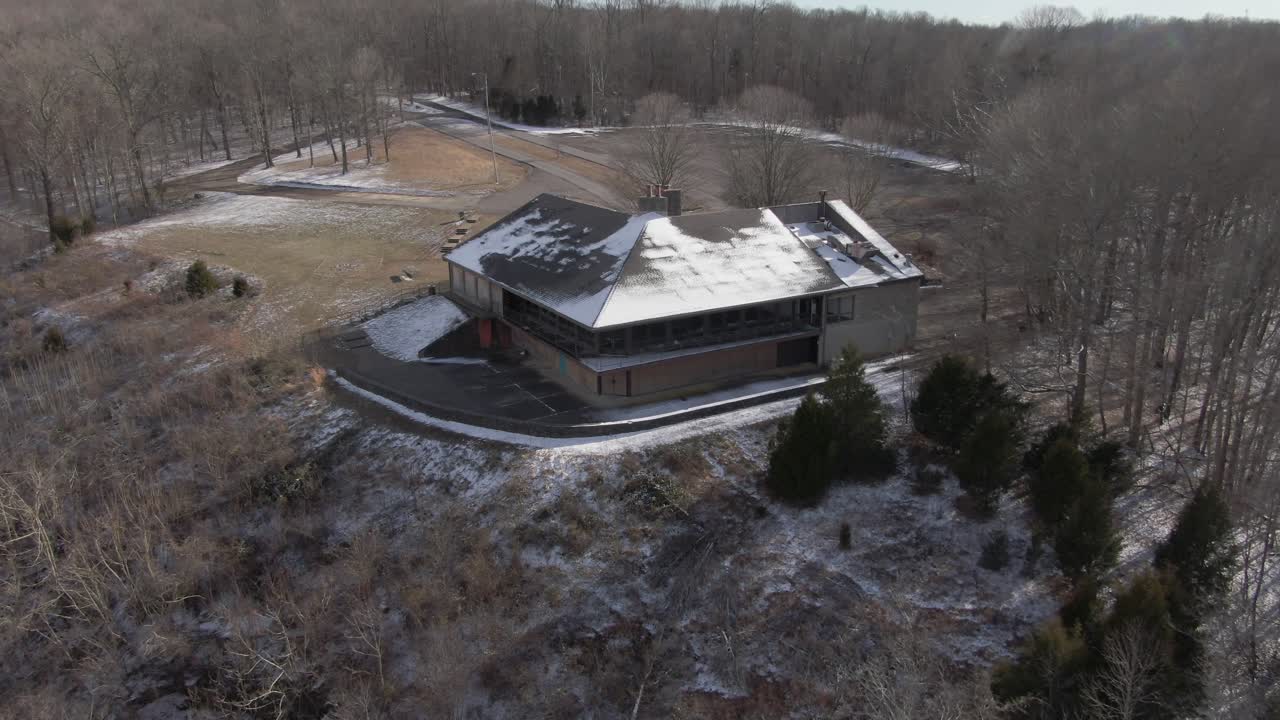 공중 드론 영상이 버려진 산장을 앞으로 돌리고 아래로 패닝합니다.