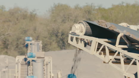 stones falling from conveyor belt, sunny dusty slow motion, asphalt quarry, paraguay, south america