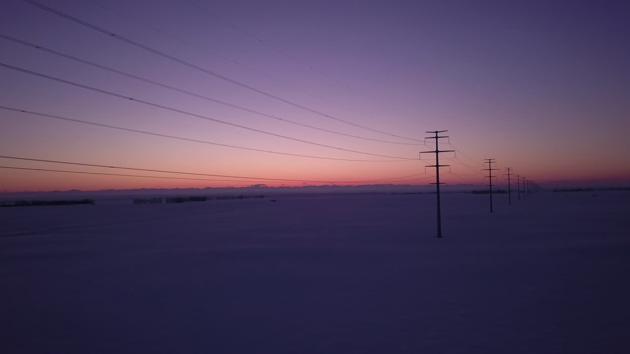 Winter Sunset over Snow Covered Field with Power Lines