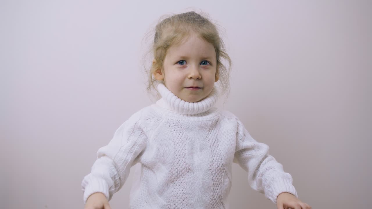 маленькая девочка в теплом свитере пытается напугать позирующую в комнате