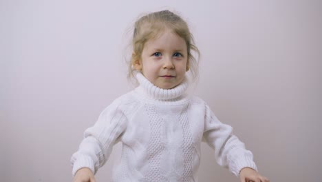 little girl in warm sweater tries to frighten posing in room