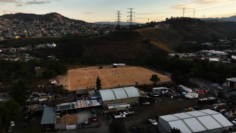 Aerial-view-away-from-a-football-field-in-the-Naucalpan-ghetto,-evening-in-Mexico-city---pull-back,-drone-shot