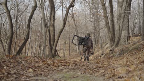 Gimbal-following-bowhunter-in-camouflage-outfit-walking-in-forest-path-during-winter
