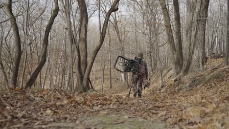 gimbal siguiendo a bowhunter en traje de camuflaje caminando por el sendero del bosque durante el invierno