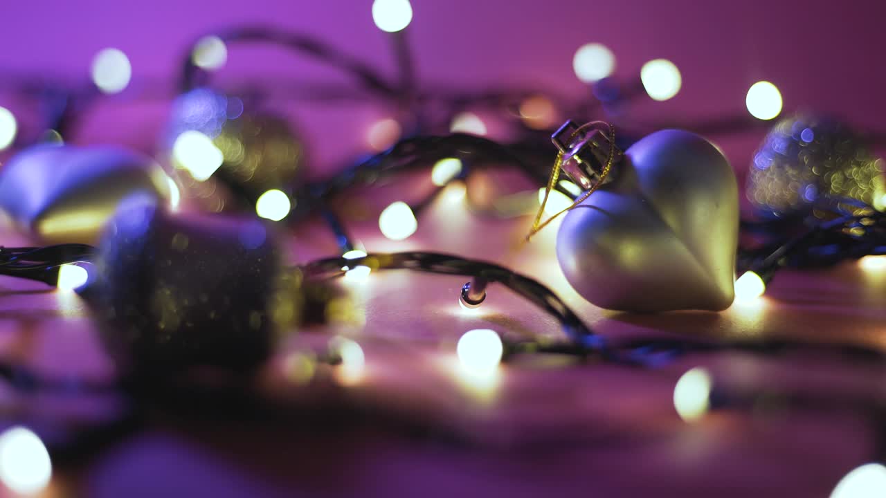 Close-up shot of garland with golden lights and christmas toys on color background. Christmas concept. Home decor. Beautiful bokeh