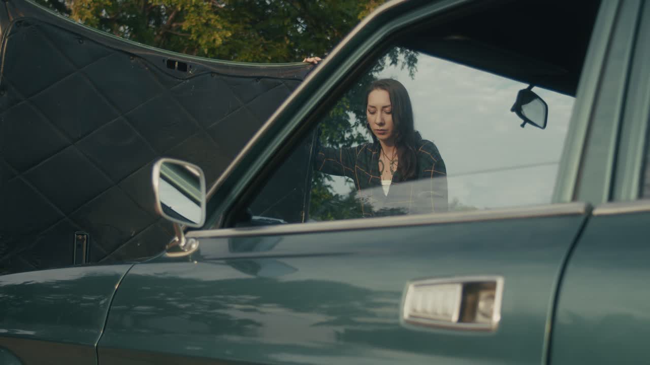 una mujer arreglando un coche averiado.