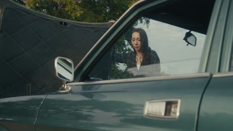 una mujer arreglando un coche averiado.