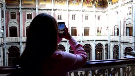 Mujer-En-Un-Balcón-Tomando-Una-Fotografía-Del-Patio-De-Las-Naciones-En-El-Palacio-Da-Bolsa,-Porto,-Portugal