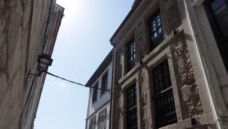 narrow alley between historic stone buildings with a bright blue sky above, daytime