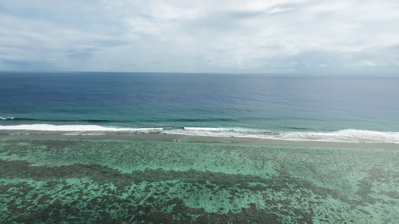 Drone panoramic overview approach of waves breaking on shallow fringing reef in ocean water