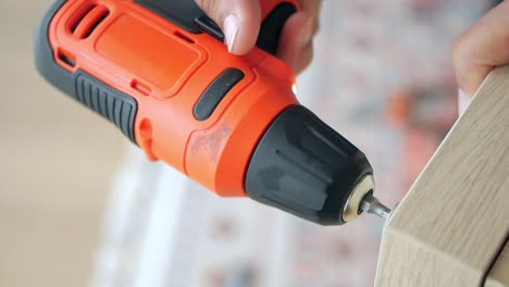 person using a cordless screwdriver to assemble furniture