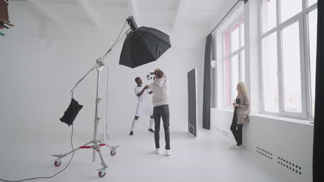 art director checking the photos on a monitor. professional crew team together in the studio. behind the scene of photo shooting professional football player and production set up in the big studio.