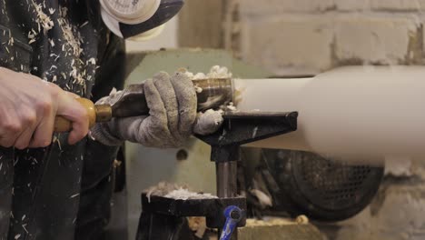 woodworker planing a table leg with wood chips flying