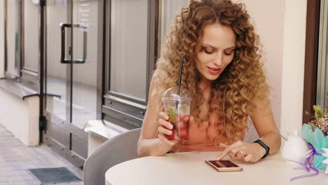 woman enjoying a drink and using her phone outdoors