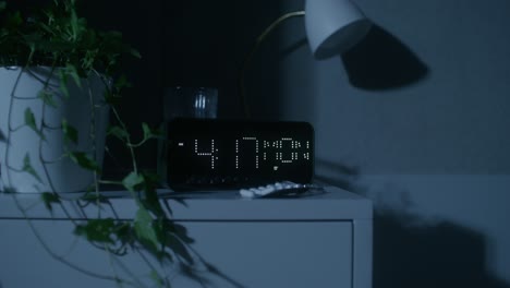 mesita de noche de dormitorio con reloj digital y planta